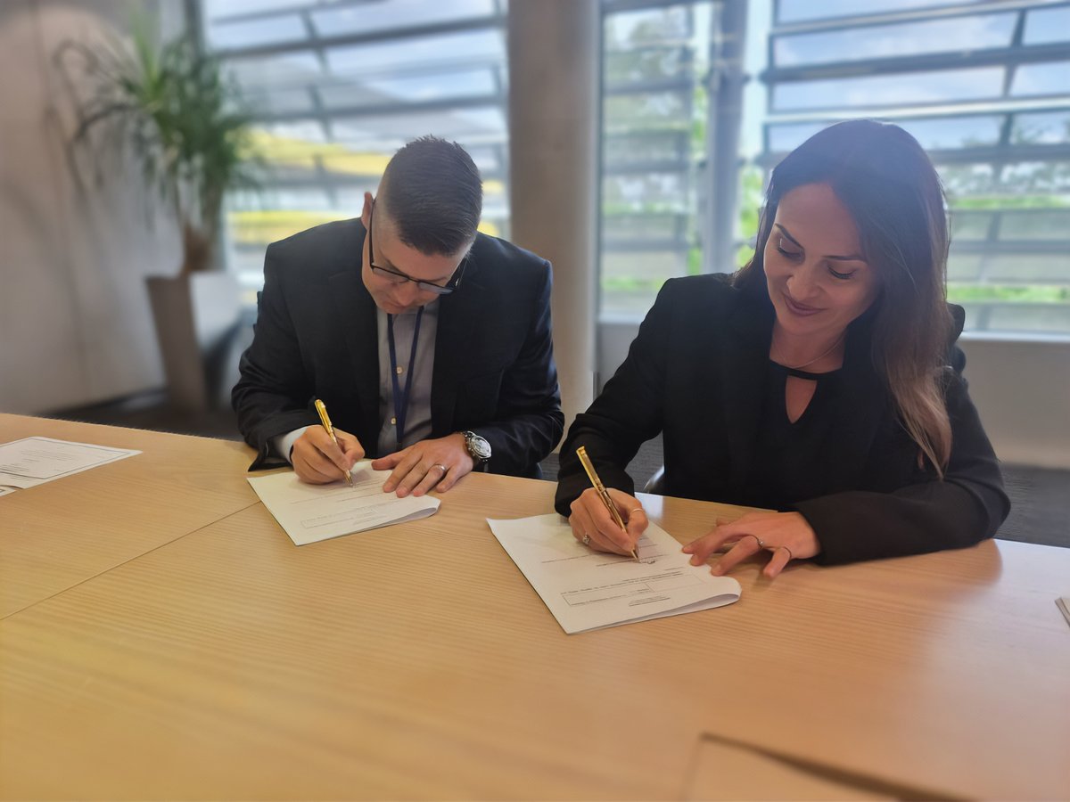 Bill Dolny, CEO of MedAire, and Elmarie Marais, CEO of GoCrisis, signing documents at a table.