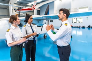Flight instructor briefing two pilots beside an aircraft in a hangar