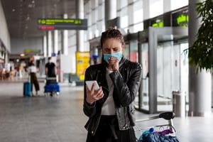 woman_wearing_mask_coughing_in_airport