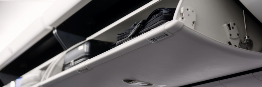 Overhead luggage bin open above airplane seats during a flight